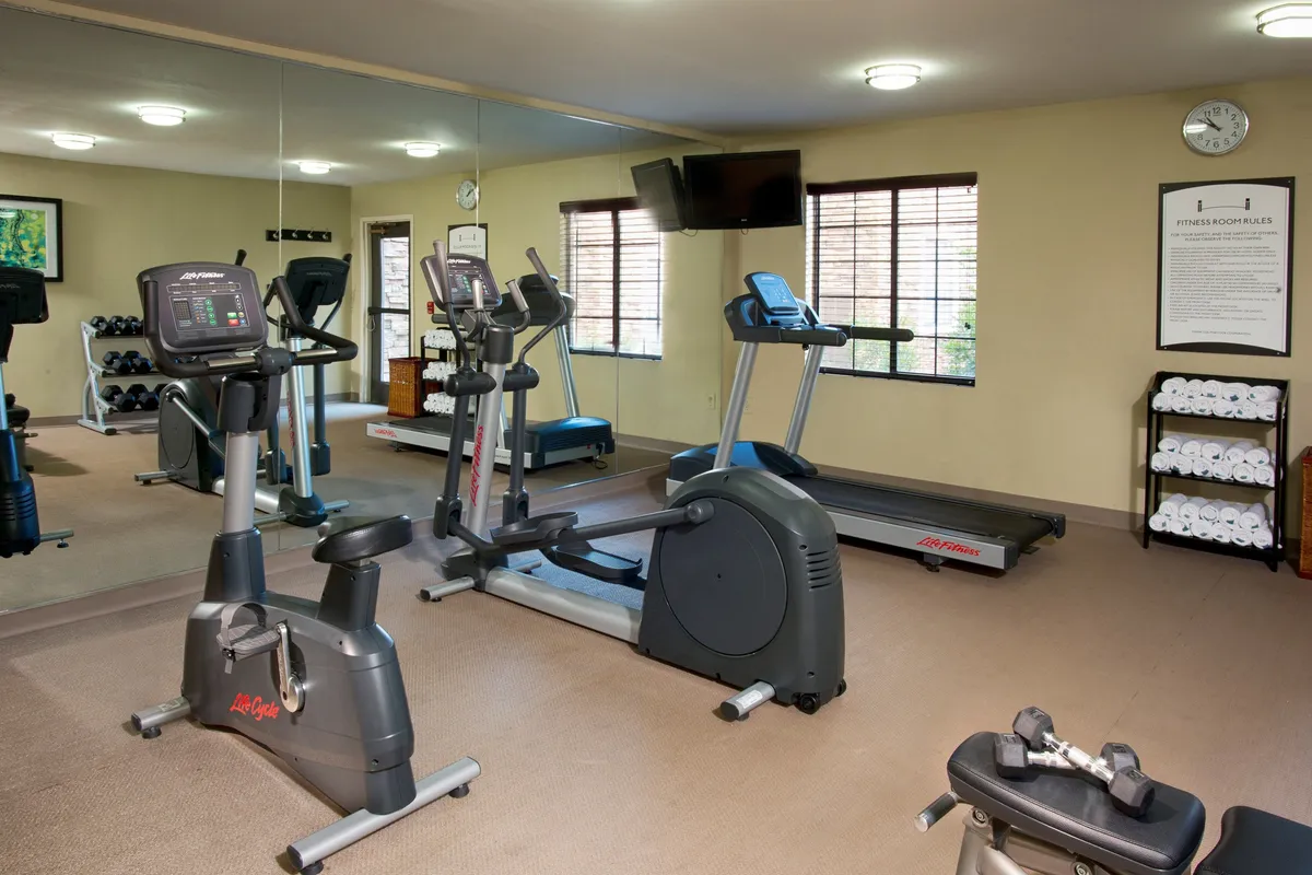 An invigorating fitness center featuring a treadmill, stationary bike, free weights, a large mirror, and a wall-mounted television, designed for diverse workouts and personal fitness sessions.