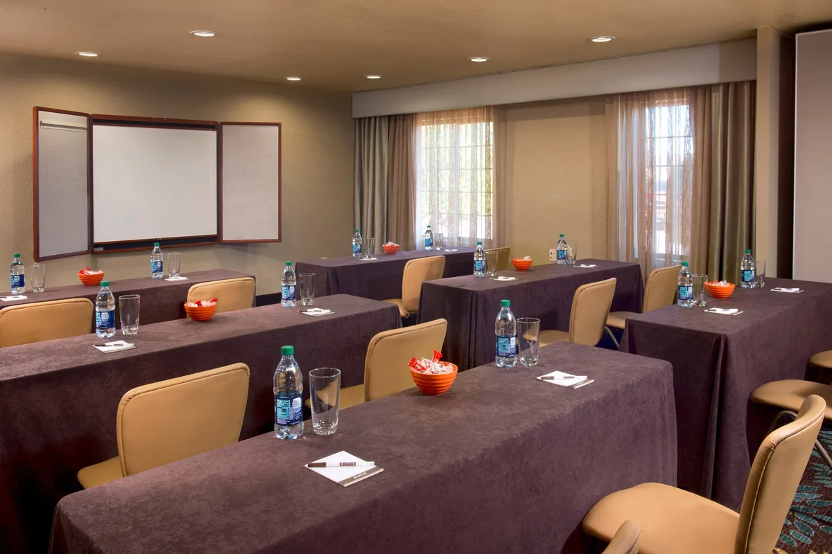 A flexible meeting space with tables laid out in a classroom style, water bottles, and snack bowls, ready for group workshops, presentations, or collaborative work sessions.