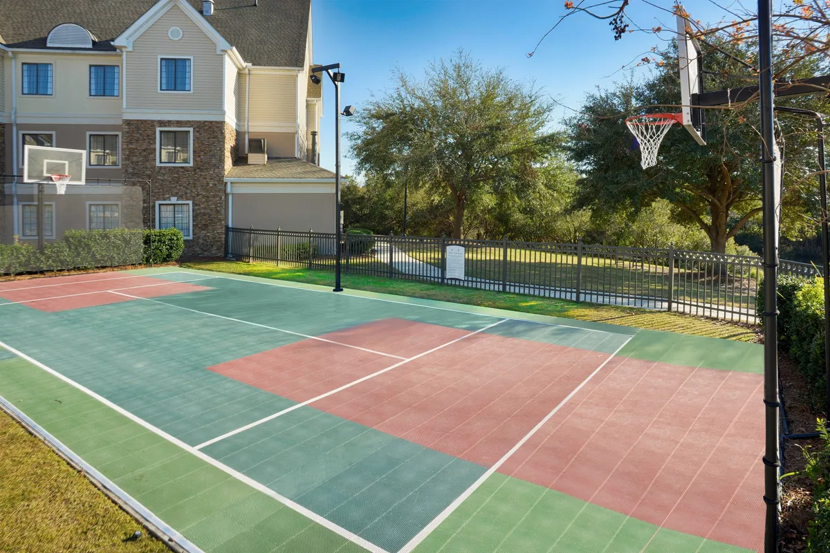 This energetic exterior shot highlights a colorful basketball court surrounded by lush greenery, with families and guests enjoying friendly games and outdoor gatherings. The playful and active vibe emphasizes the fun available just outside the hotel doors.