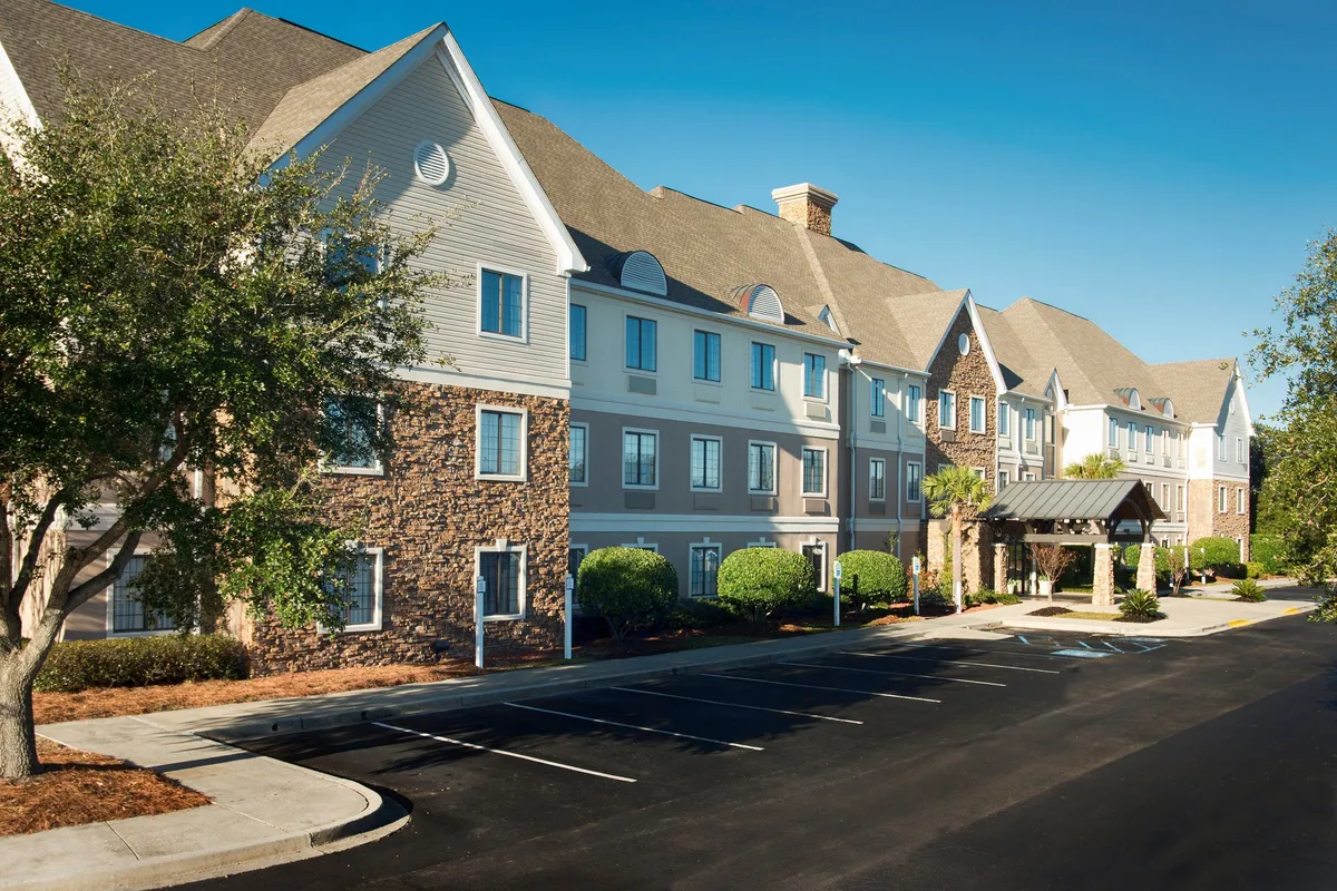 The main entrance to the property, framed by landscaped bushes and a textured stone facade, exudes a sense of arrival and comfort. The welcoming entryway sets the tone for guests as they check in or return from exploring the area.