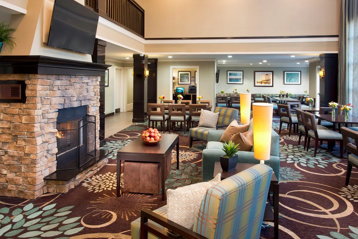 A cozy, well-lit interior featuring a fireplace, comfortable seating, dining tables, and decorative lighting. The room feels inviting and ideal for gathering, dining, or relaxing at any time of day.